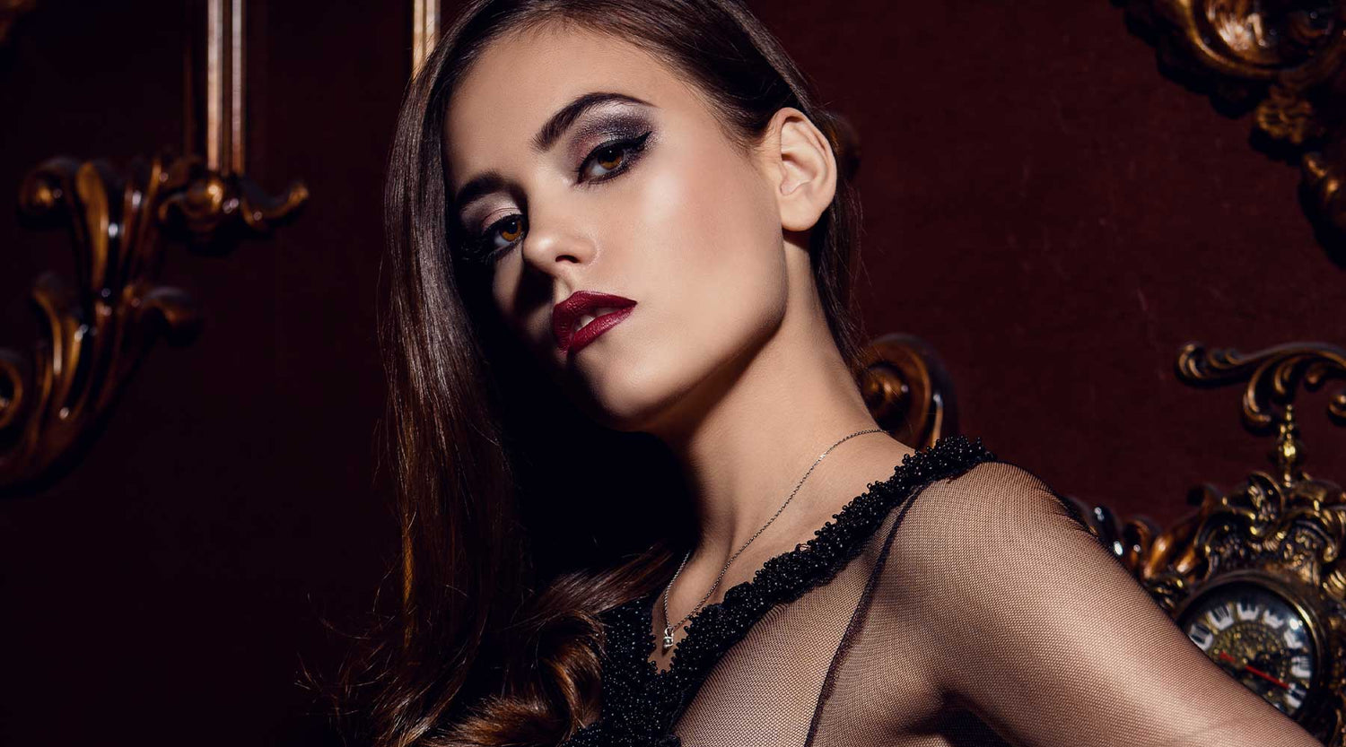 Beautiful dark haired female with smokey eye makeup and plum lipstick wearing an elegant black top.