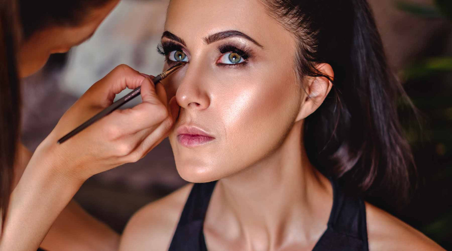 Makeup artist applying eyeliner to model with London Copyright makeup brush.