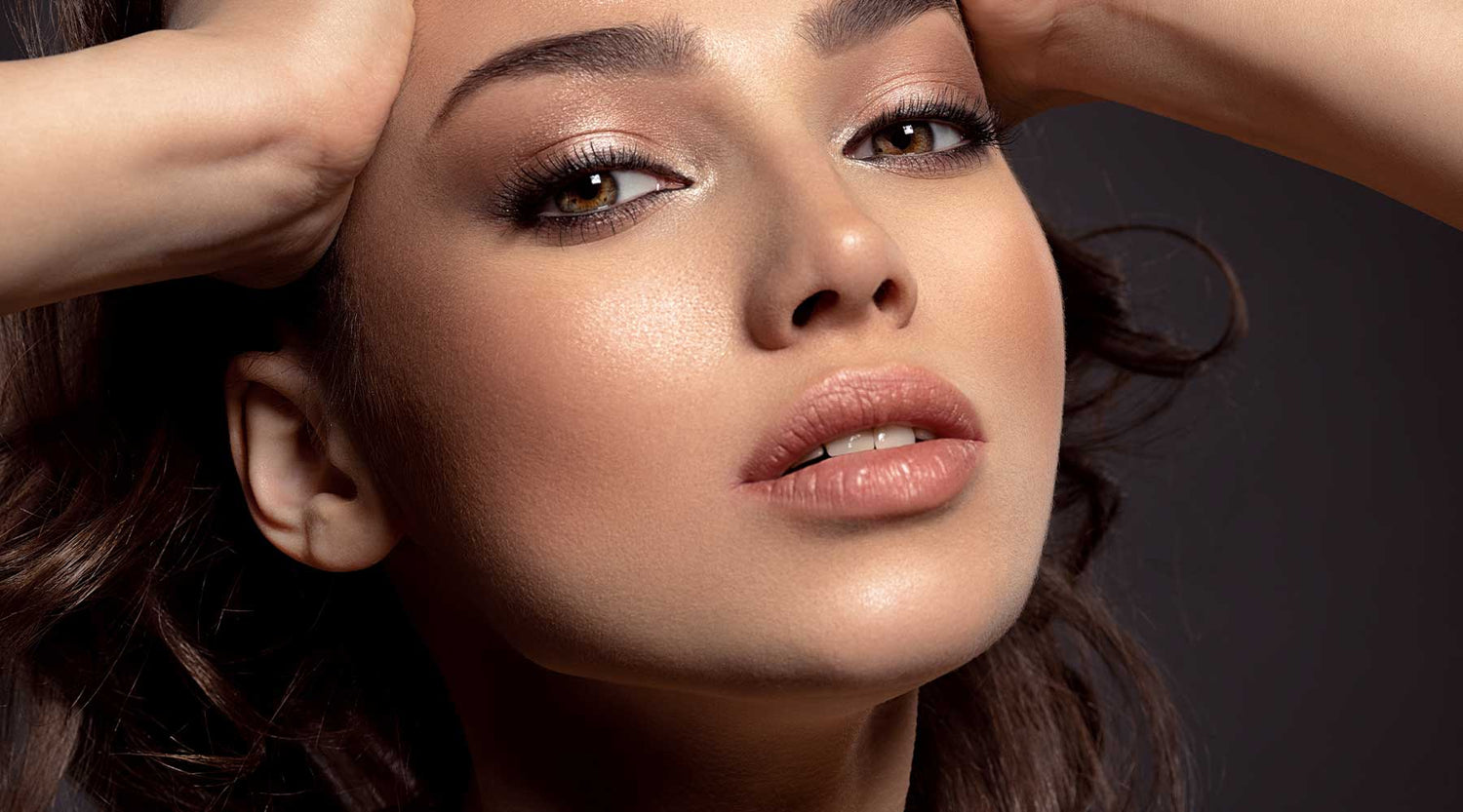 Close up of a beautiful model with brown glam makeup and soft nude lip colour.