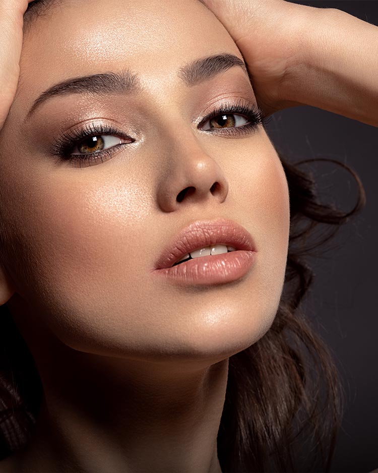 Close up of a beautiful model with brown glam makeup and soft nude lip colour.